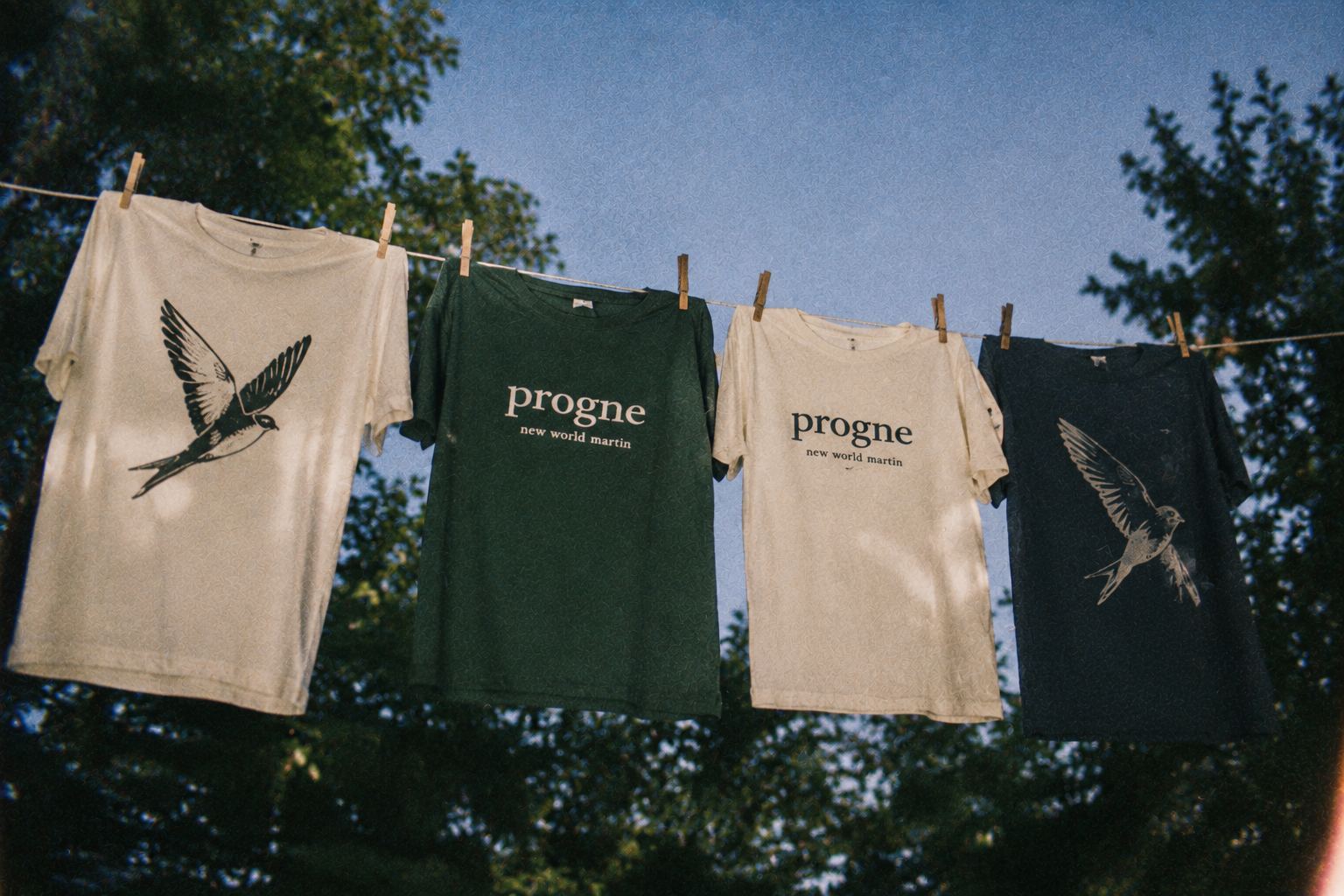 Four Progne tees in different colorways drying on a clothesline