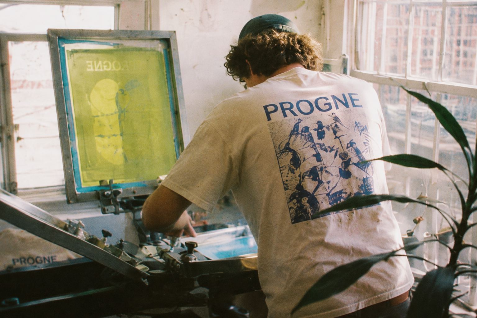 Pulling a print on the press, multi-bird design on a cream tee